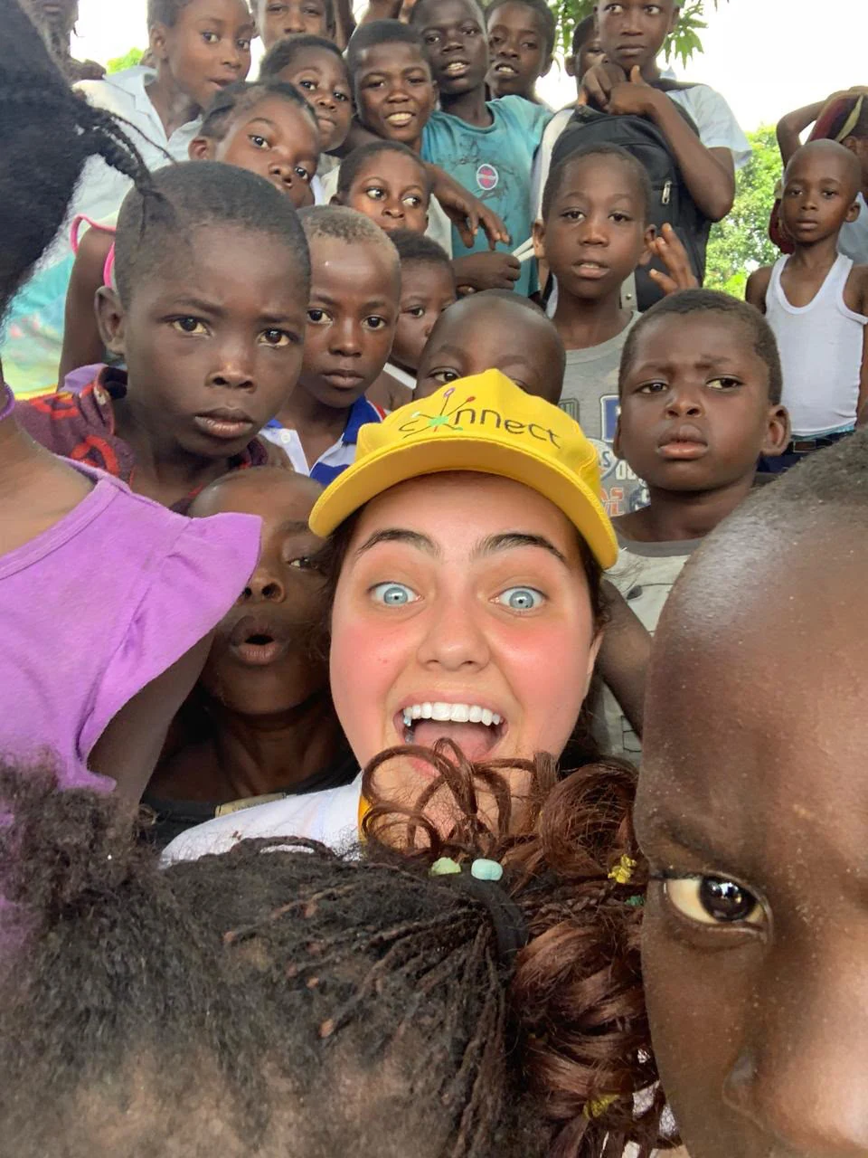 Voluntária cercada por crianças durante uma ação da MBA Maluta Foundation